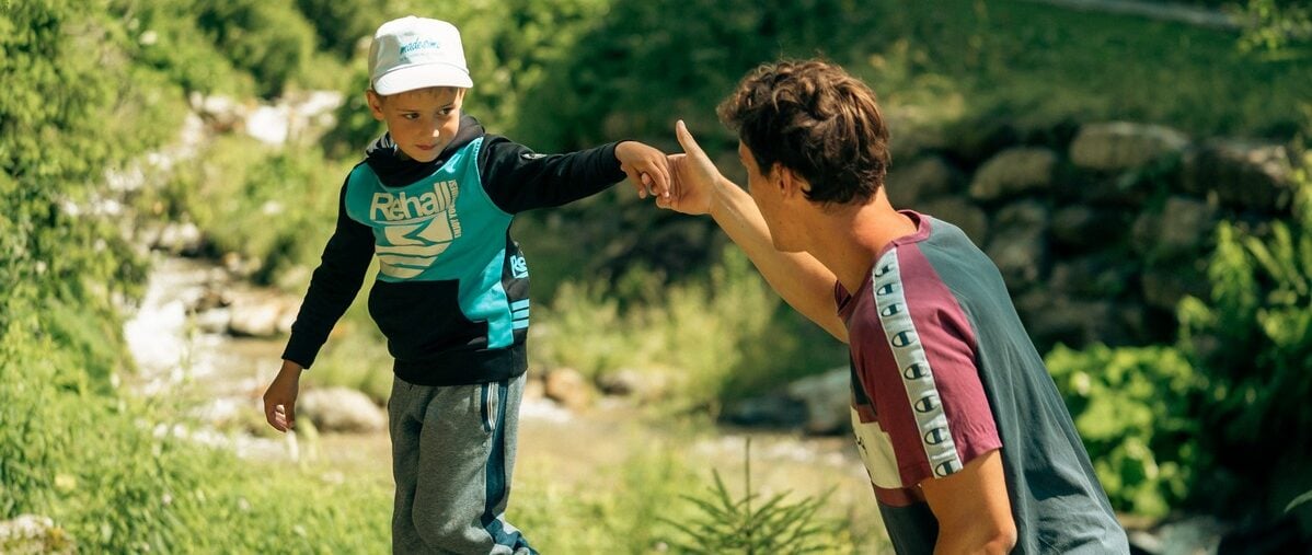 uomo tiene per mano bimbo sul muretto fiume
