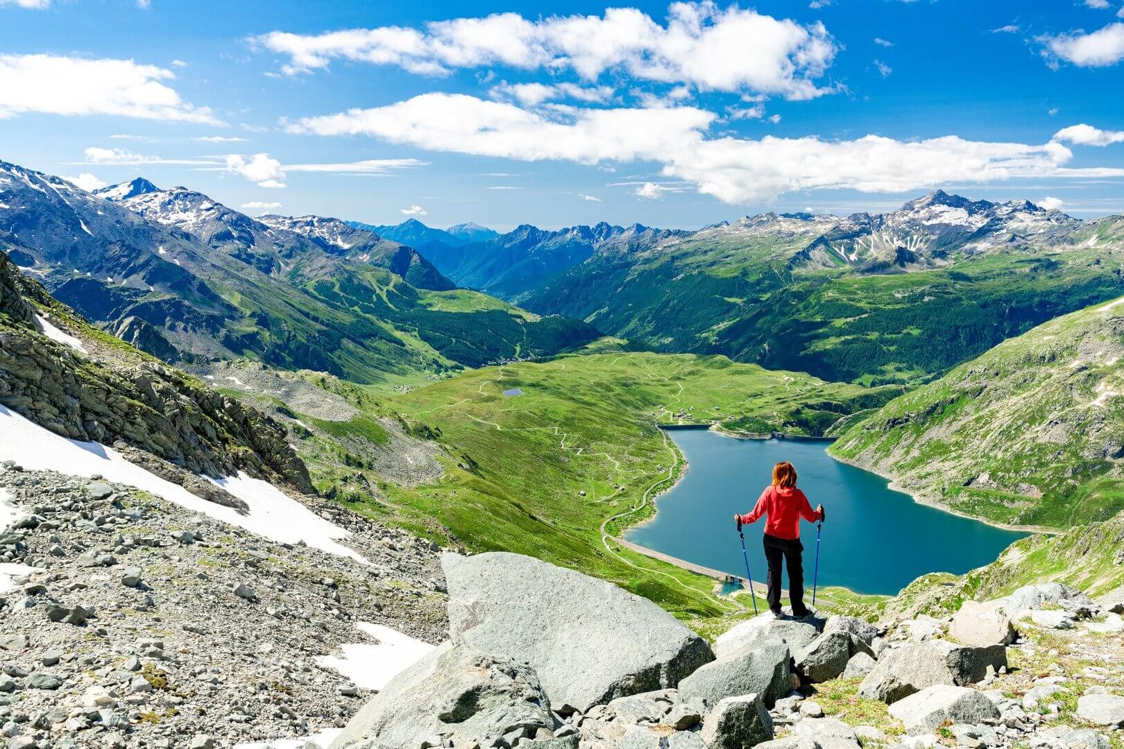 Donna in cammino ammira il lago di Montespluga vicino a madesimo